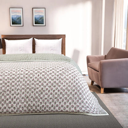 Bedroom with a bed featuring a floral-patterned comforter, a chair, and framed pictures on the wall.