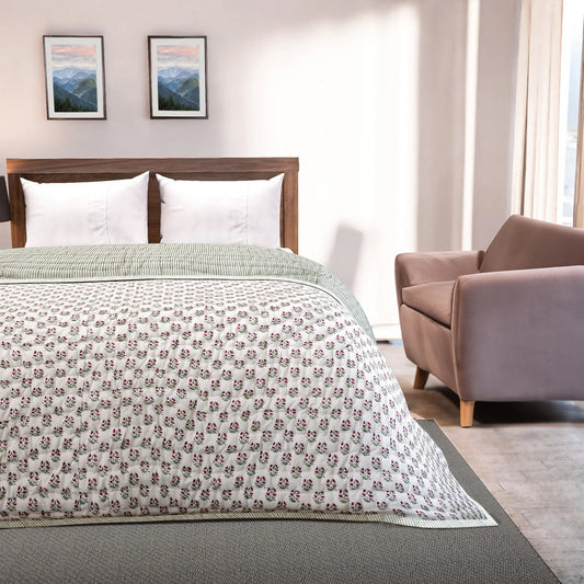 Bedroom with a bed featuring a floral-patterned comforter, a chair, and framed pictures on the wall.