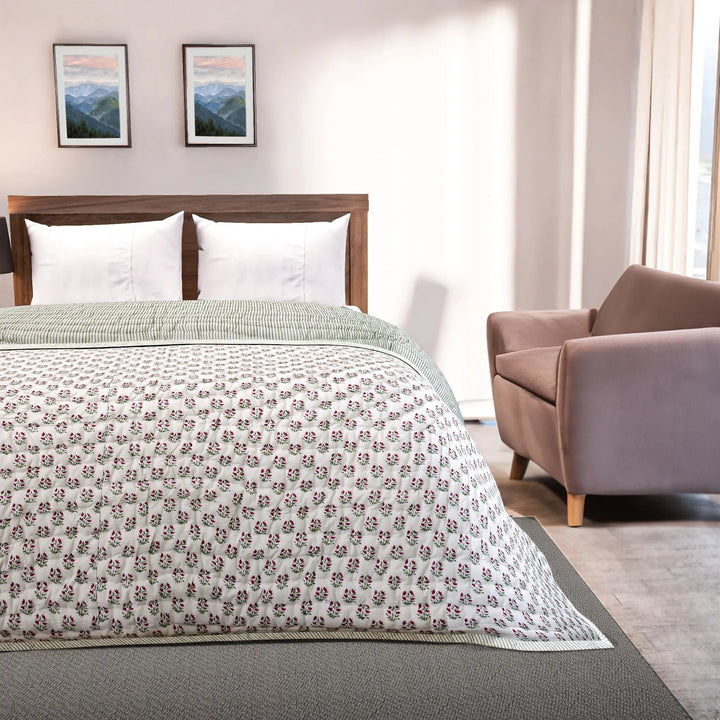 Bedroom with a bed featuring a floral-patterned comforter, a chair, and framed pictures on the wall.