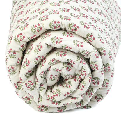 Rolled-up floral-patterned quilt on a white background