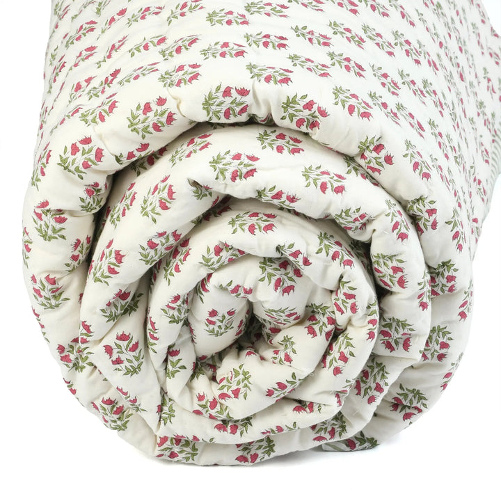 Rolled-up floral-patterned quilt on a white background