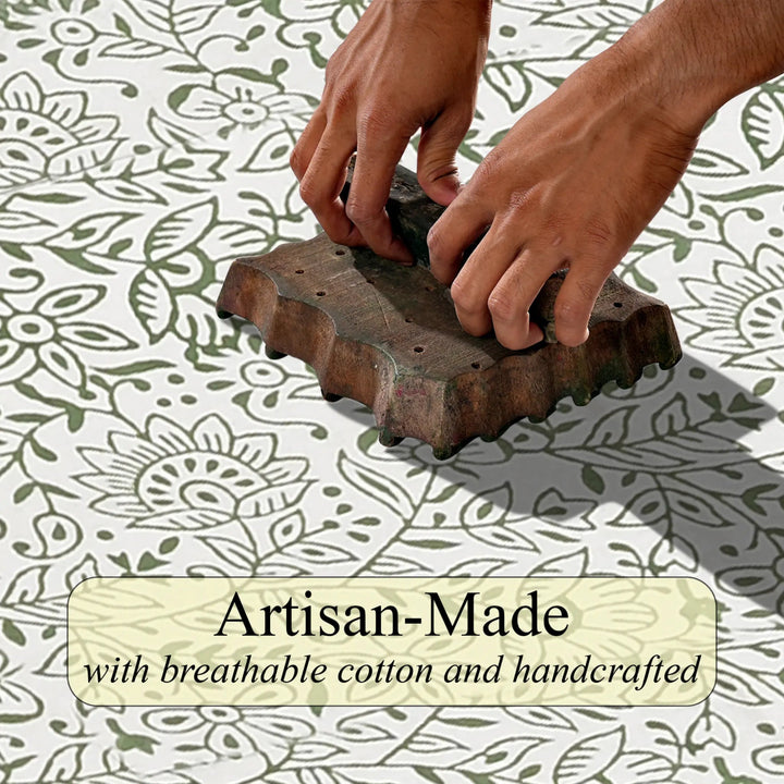 Hand using a wooden block to stamp a floral pattern on fabric with &
