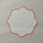 White linen round table mats with scallop edges in orange for table decor