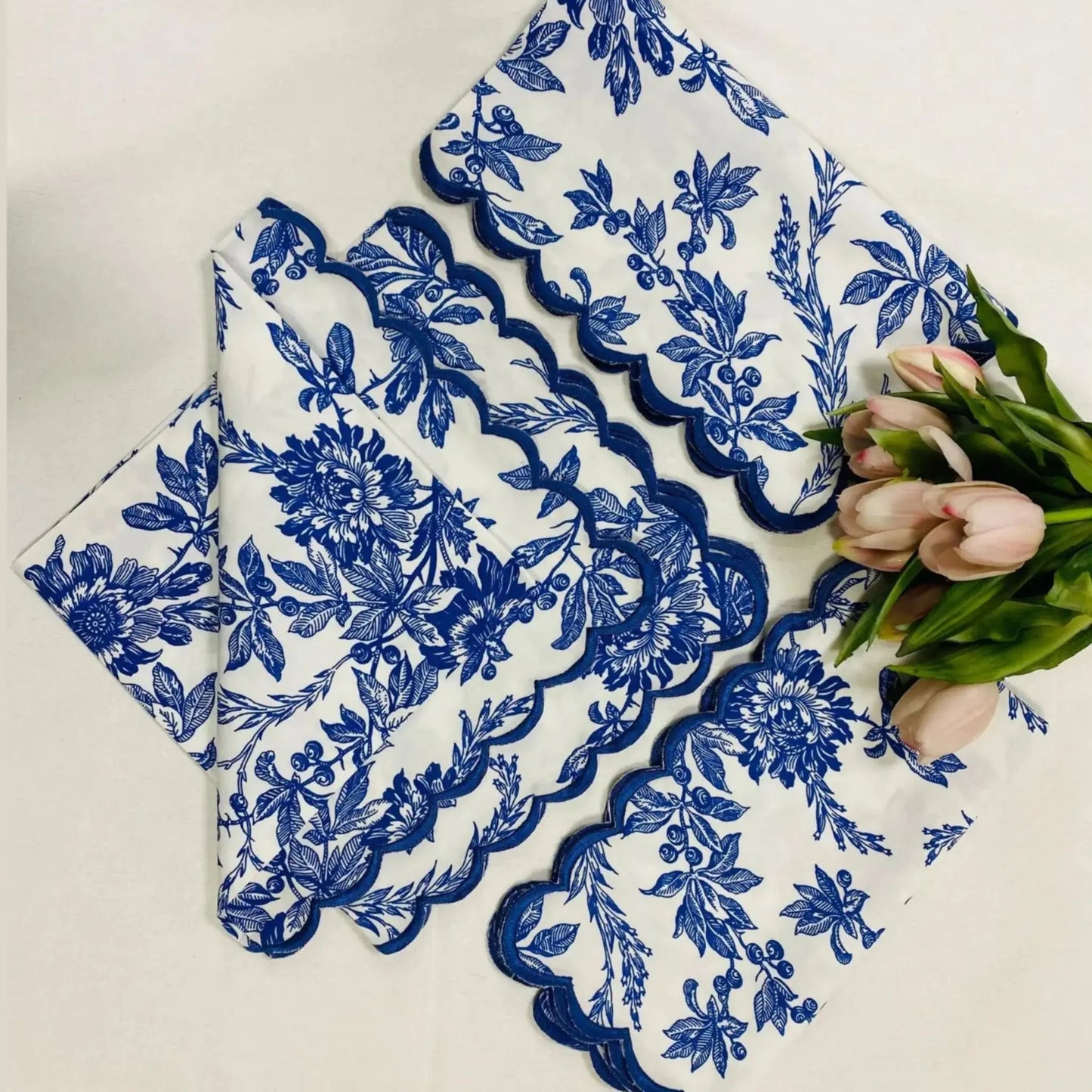 Set of blue floral lace doilies on a white surface with tulips.