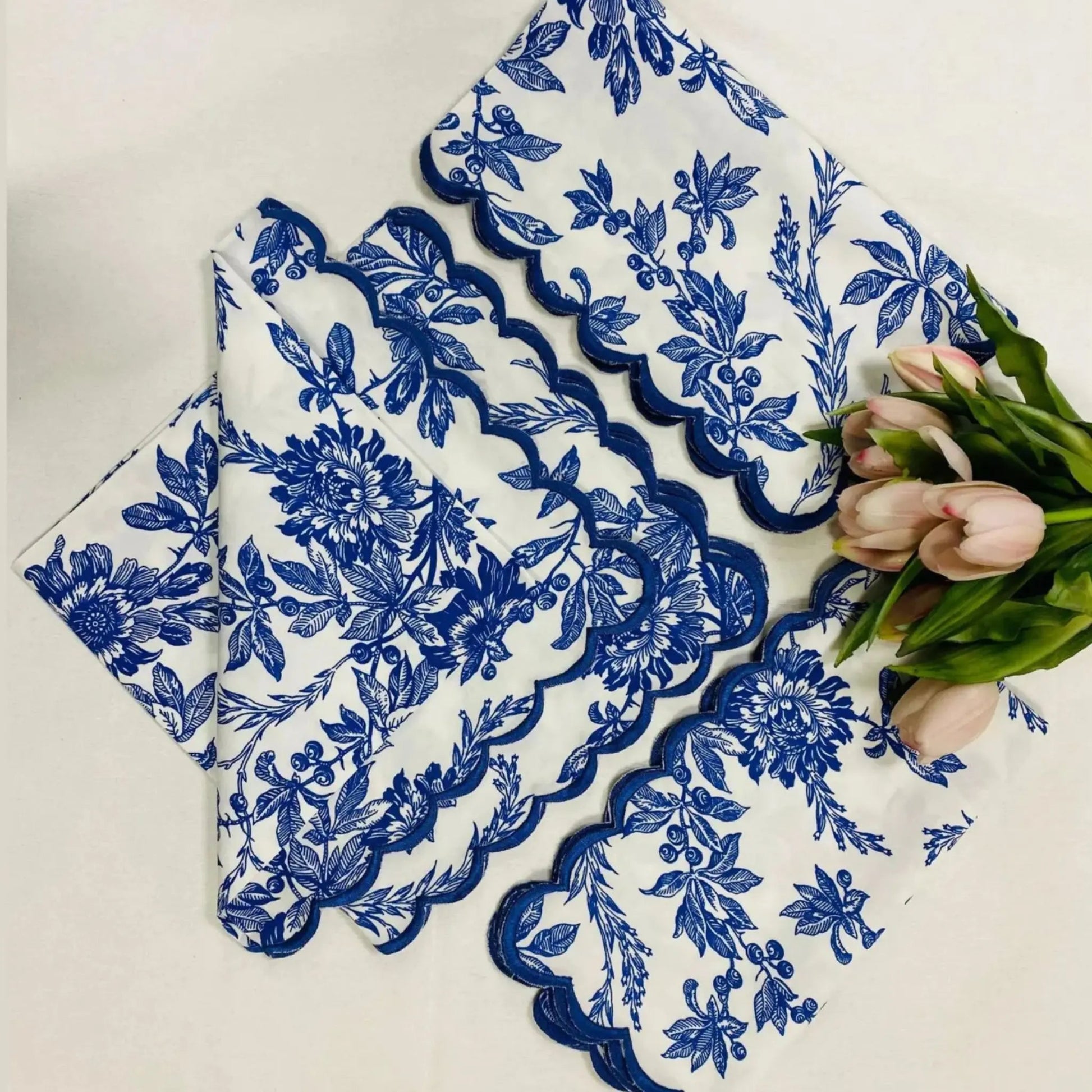 Set of blue floral lace doilies on a white surface with tulips.