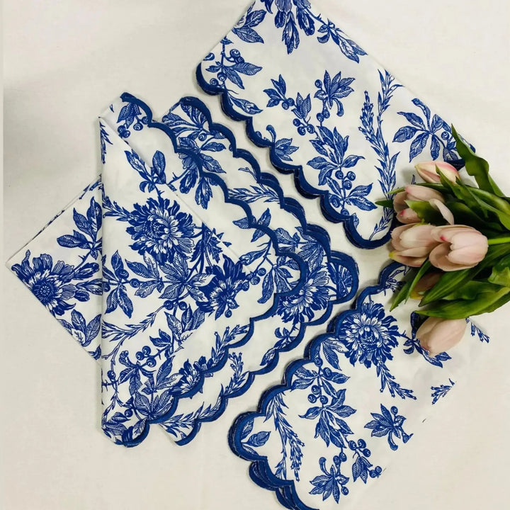 Set of blue floral lace doilies on a white surface with tulips.