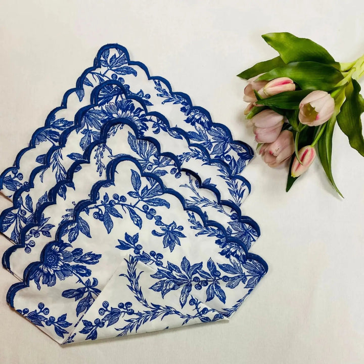 Set of blue floral-patterned napkins on a white surface with pink tulips.