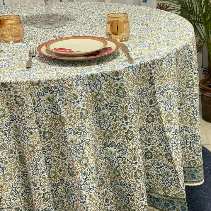 Patterned tablecloth on a round table with plates and glasses.