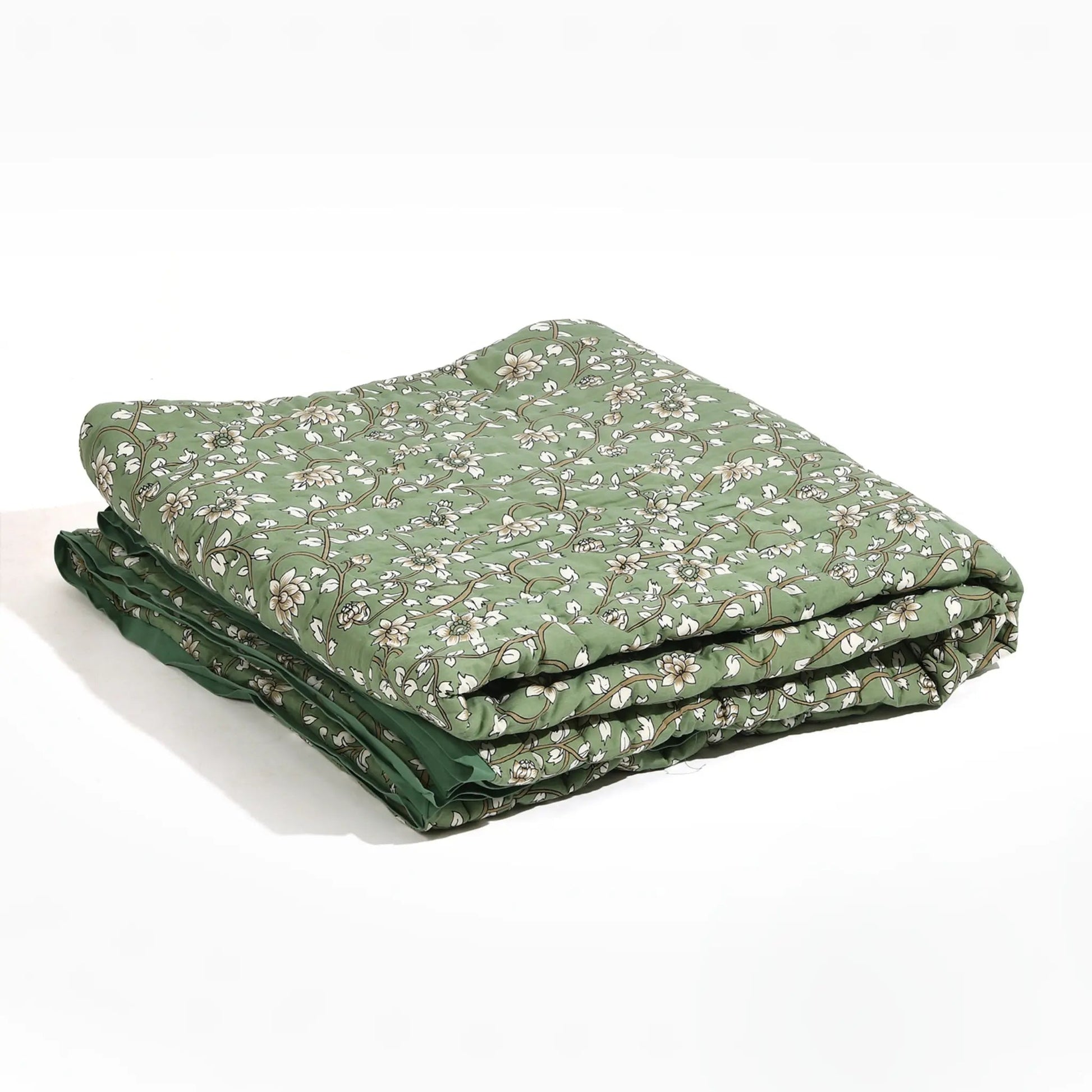Folded green quilt with floral pattern on a white background