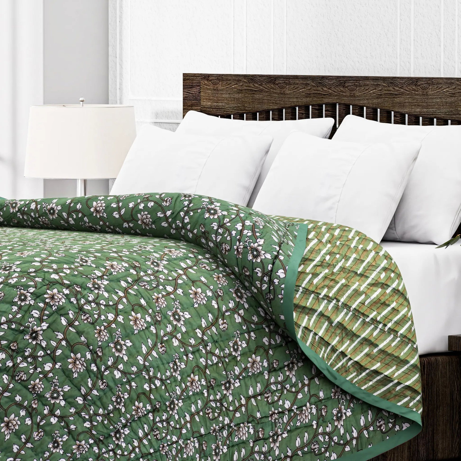 Green floral quilt on a bed with white pillows and a wooden headboard.