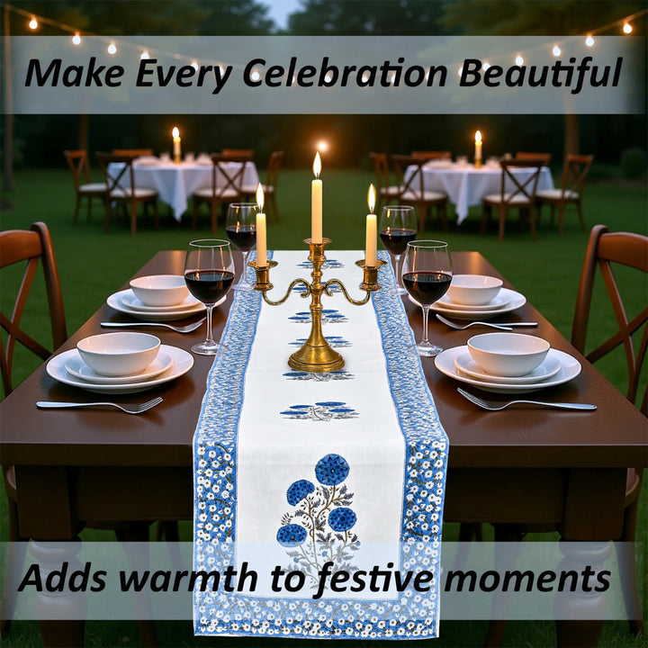 Dining table set with a floral table runner, candles, and wine glasses outdoors.