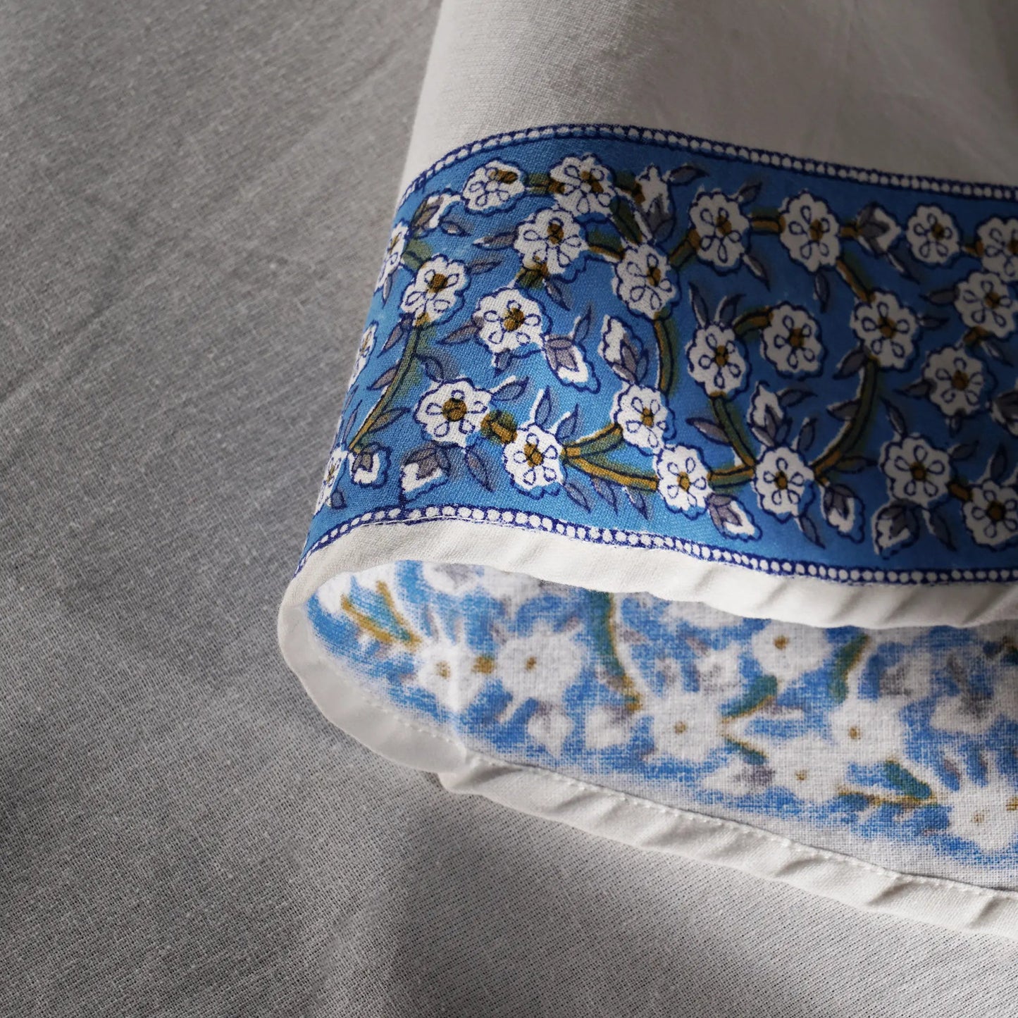 Close-up of a pillow with blue floral pattern on a gray fabric background