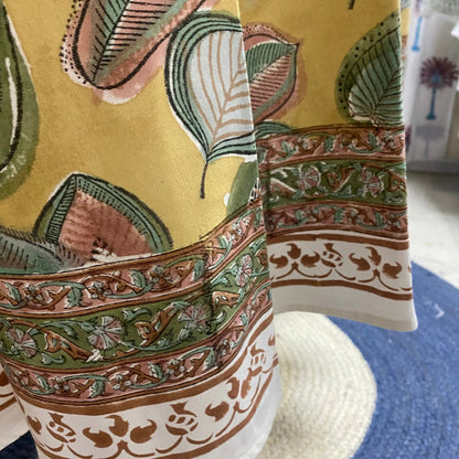 Close-up of a patterned fabric with intricate designs on a yellow background.