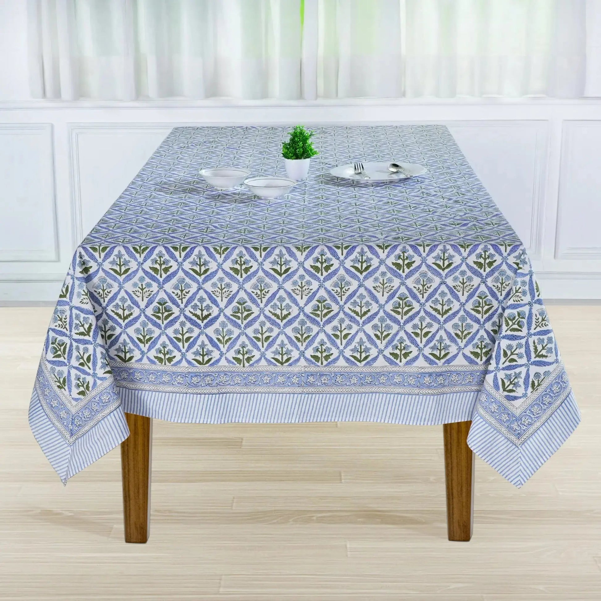 Tablecloth with geometric pattern on a wooden table in a room with white curtains.