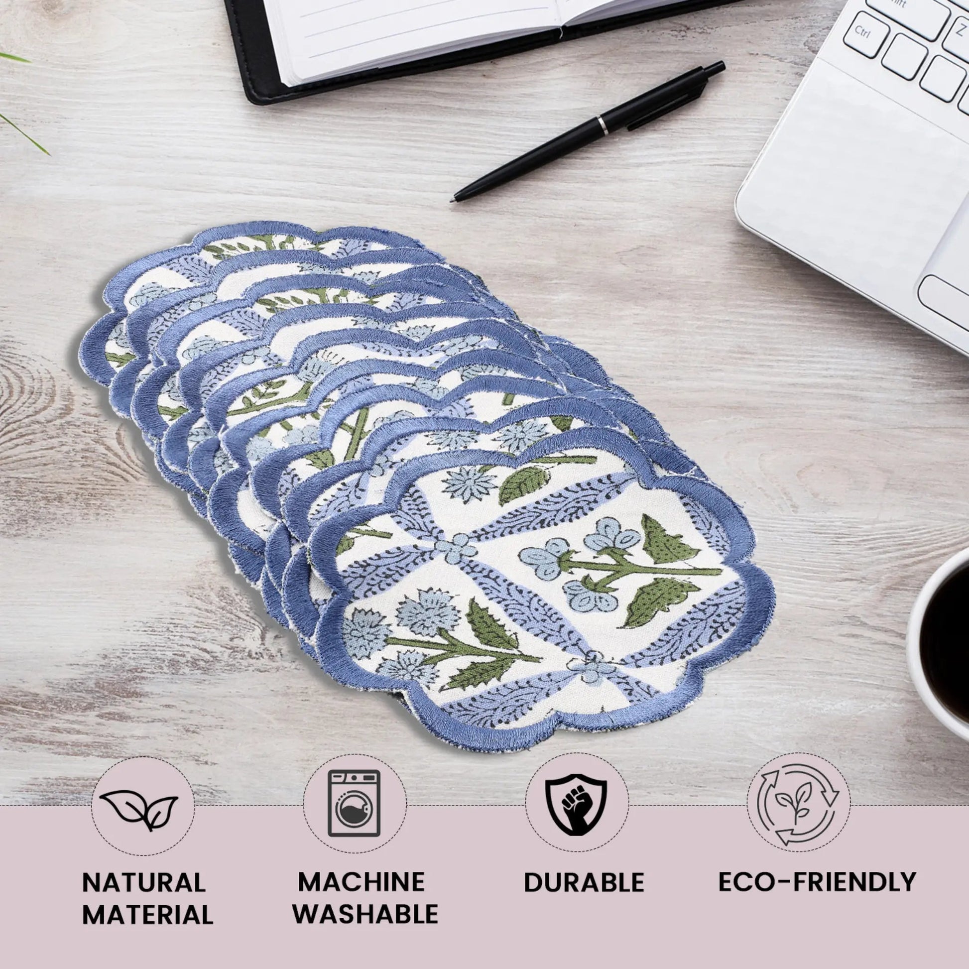 Set of reusable menstrual pads with floral design on a desk with office supplies.
