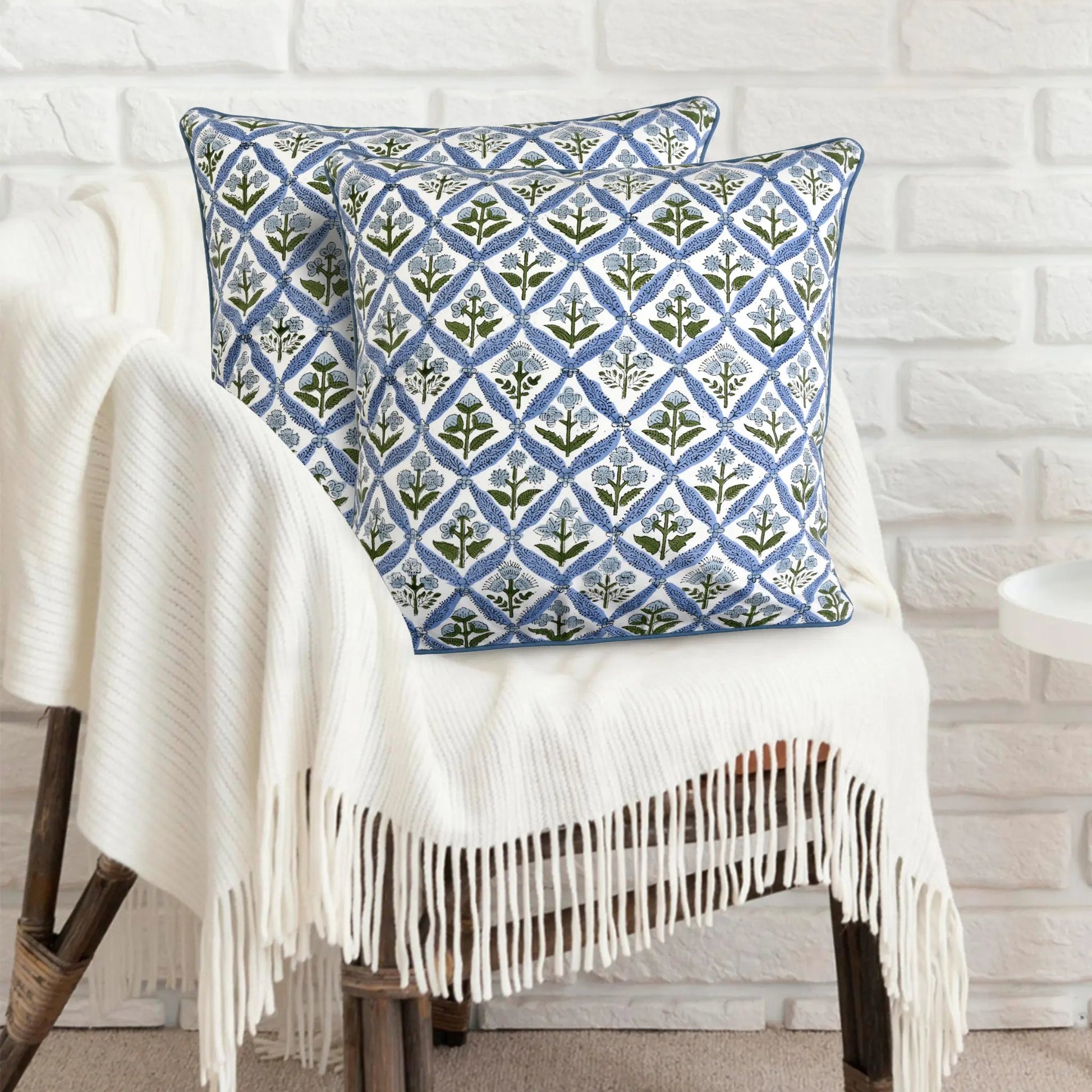 Decorative pillow with geometric pattern on a white chair against a white brick wall.