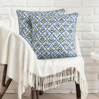 Decorative pillow with geometric pattern on a white chair against a white brick wall.