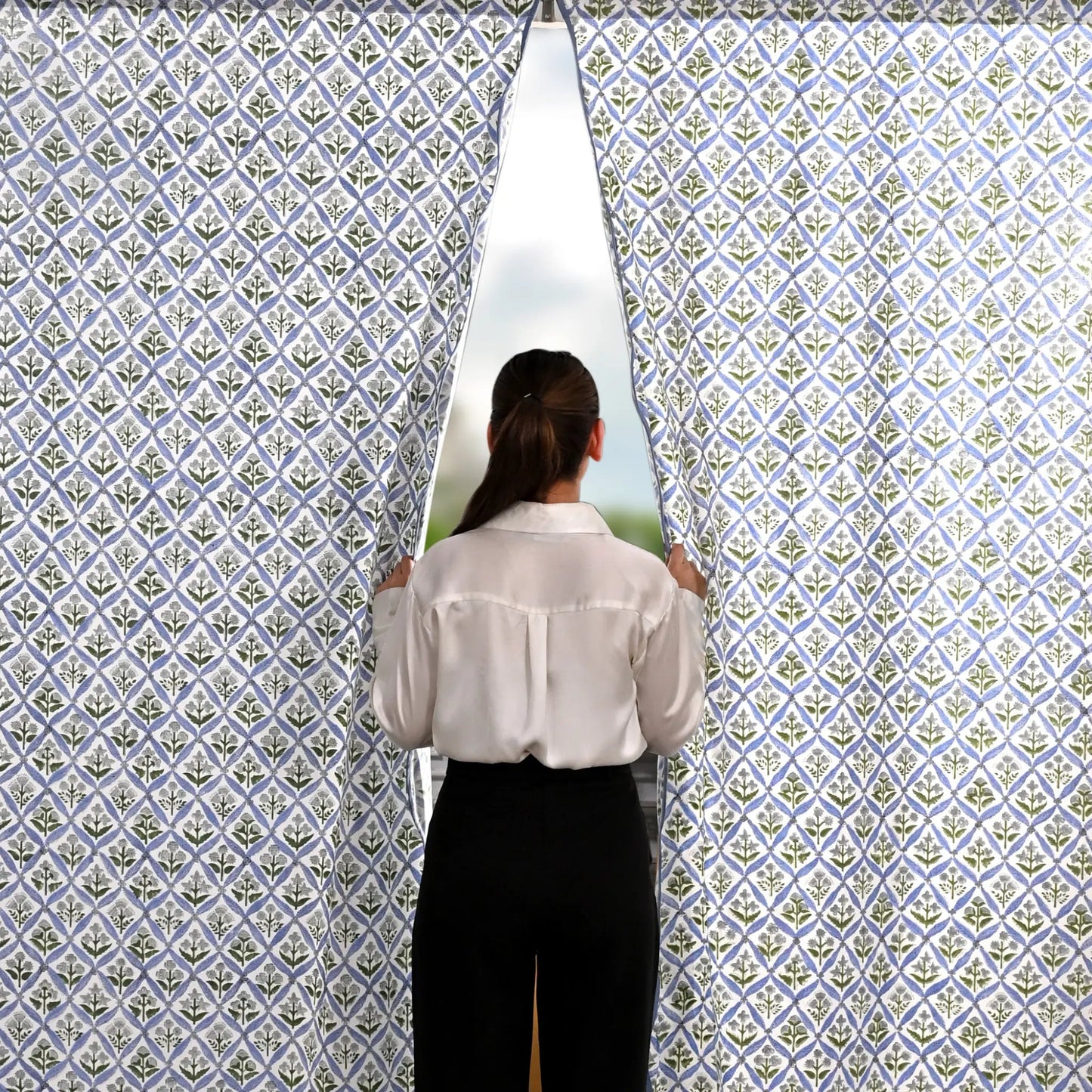 Person standing in front of a patterned wall with a window showing a scenic view.