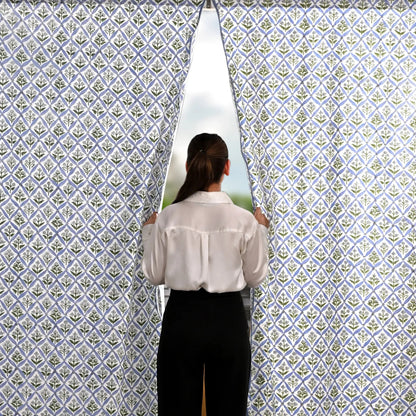Person standing in front of a patterned wall with a window showing a scenic view.