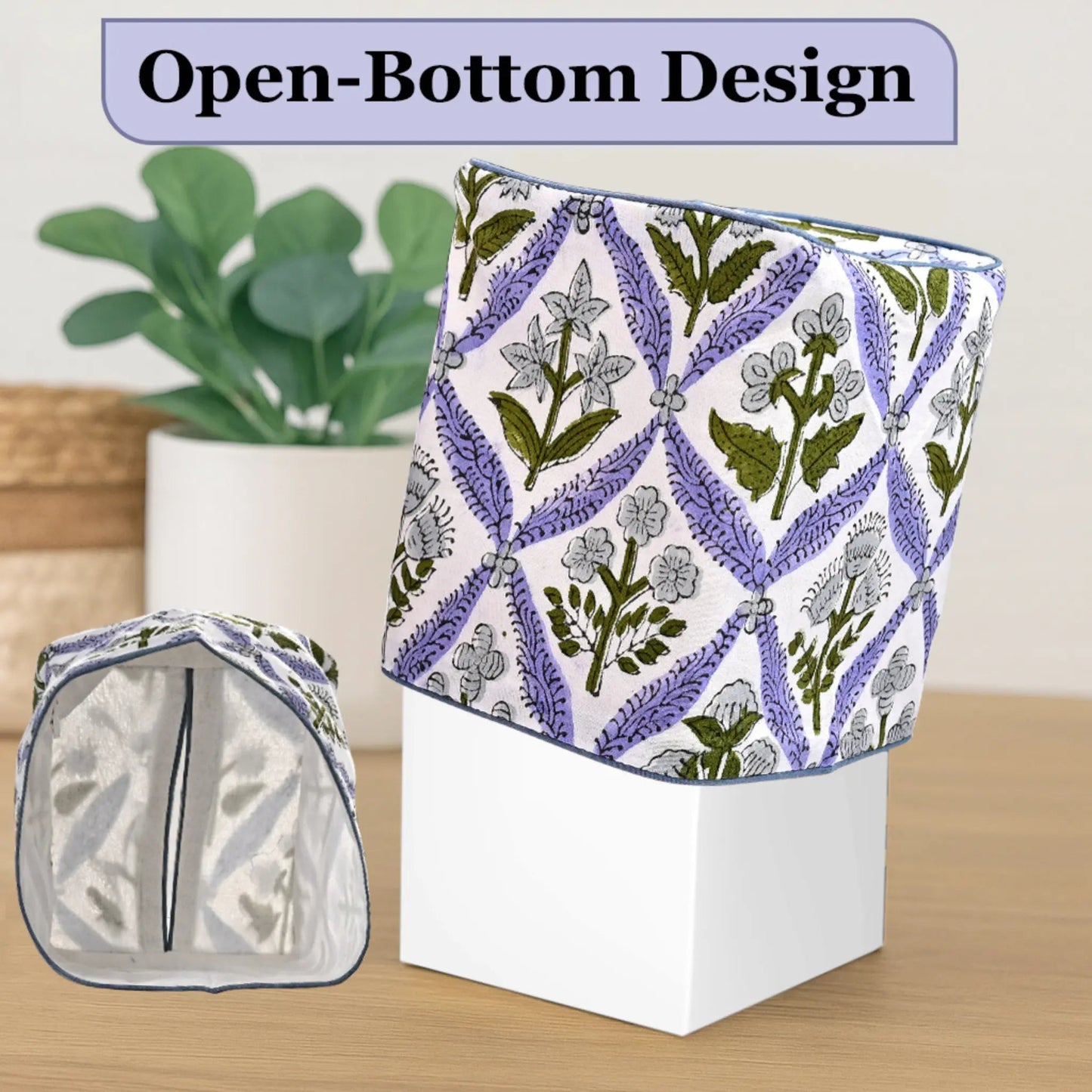 Floral-patterned fabric with open-bottom design on a white box, plant in the background.