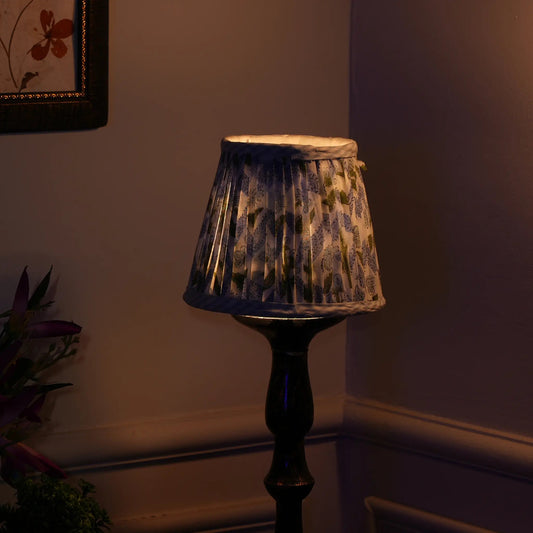 Decorative lamp with a patterned shade in a dimly lit room.