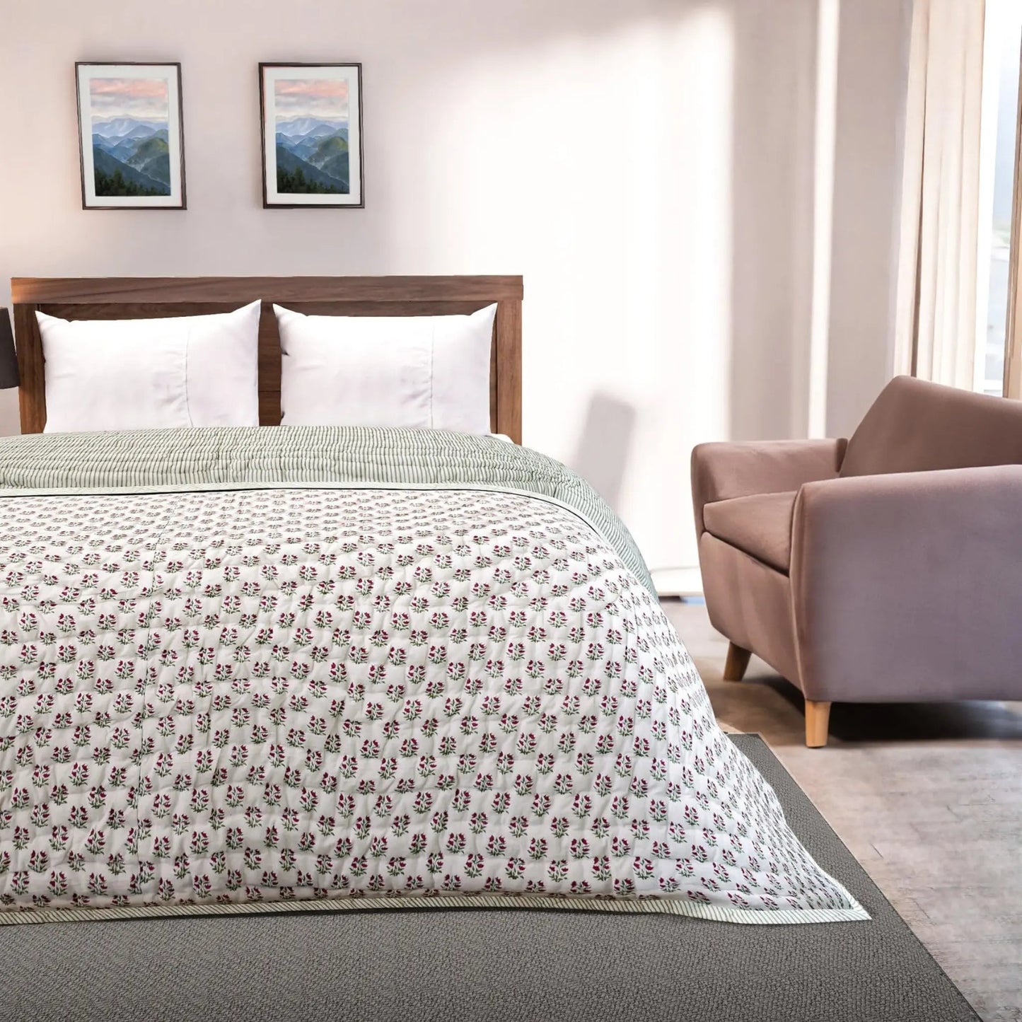 Bedroom with floral-patterned comforter on a bed, armchair, and framed pictures on the wall.