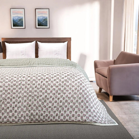 Bedroom with floral-patterned comforter on a bed, armchair, and framed pictures on the wall.