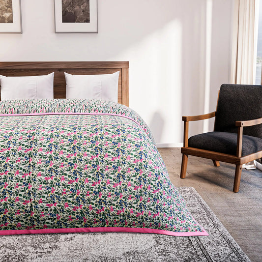 Bed with floral quilt in a bedroom setting with a chair and artwork on the wall.