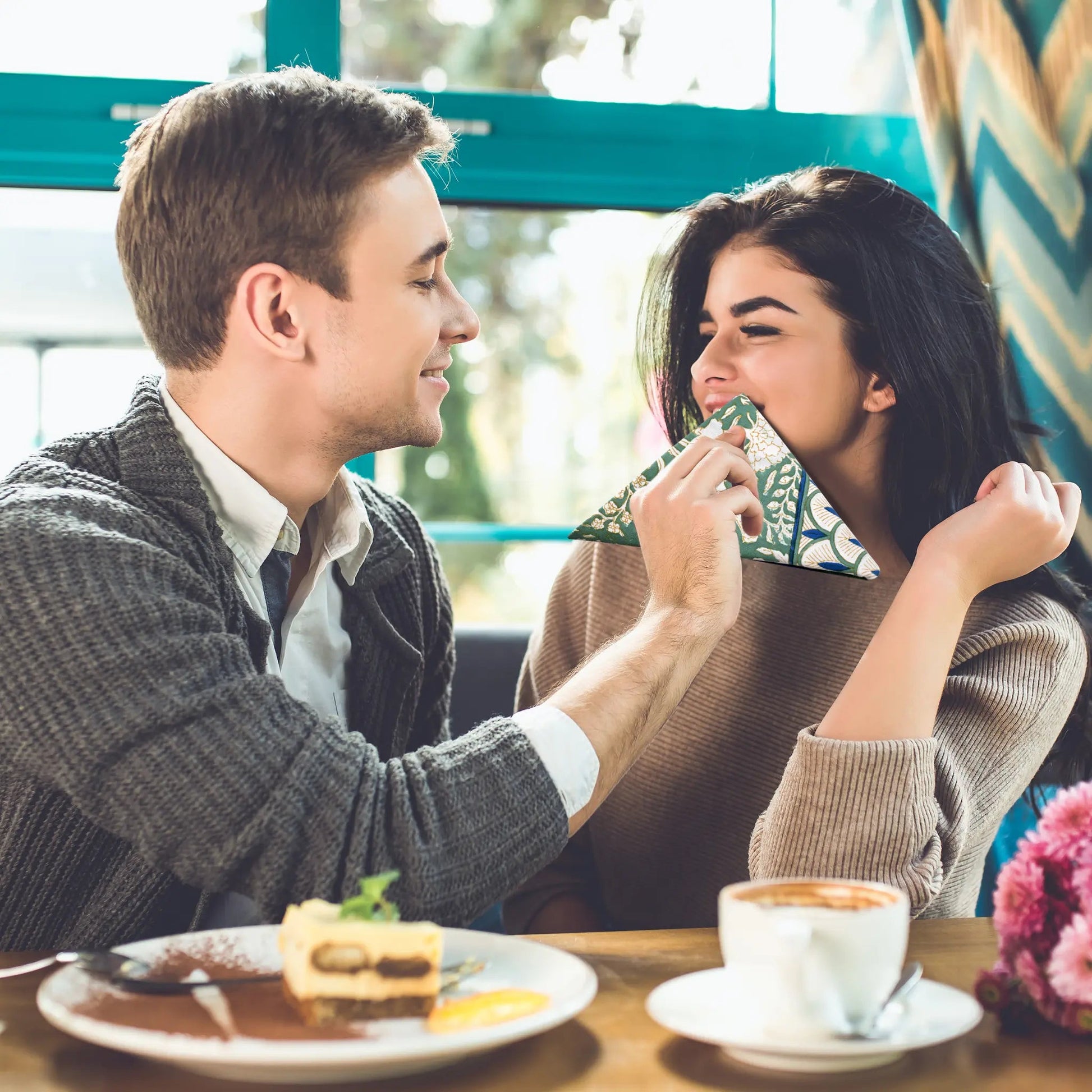 Man and woman sharing a moment at a cafe with food and coffee on the table.