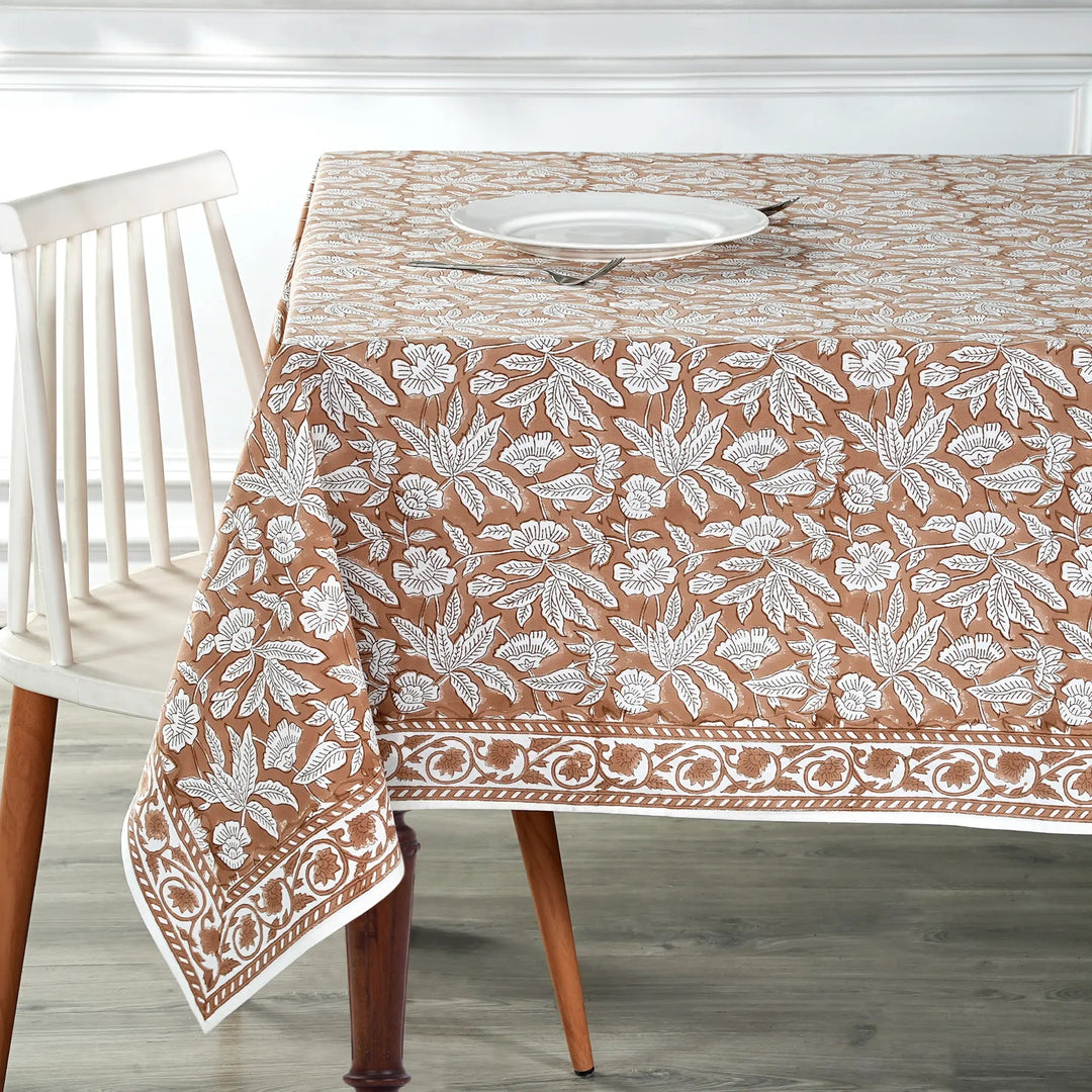 Tablecloth with floral pattern on a wooden table and chair.