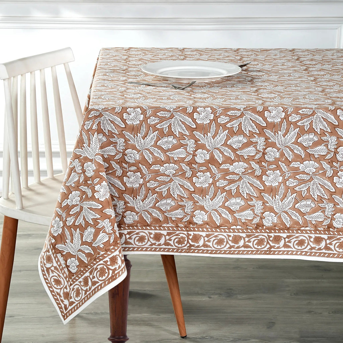 Tablecloth with floral pattern on a wooden table and chair.