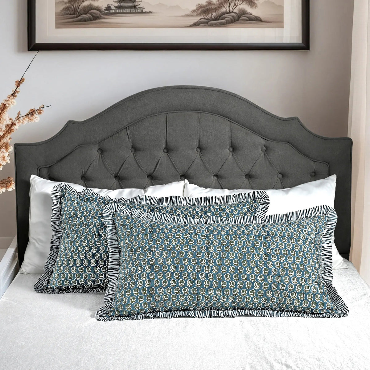 Large block print cotton pillows styled on gray upholstered bed.