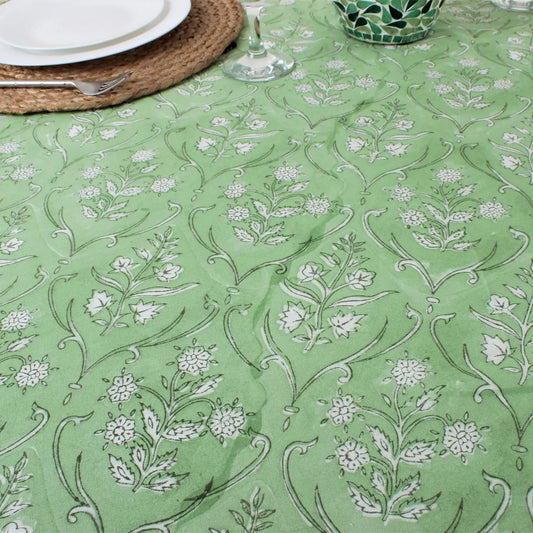 Green tablecloth with white floral pattern on a table setting.