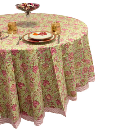 Round table with a floral tablecloth, plates, and glasses on a white background