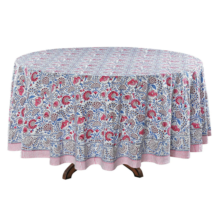 Round floral-patterned tablecloth on a wooden table with a white background
