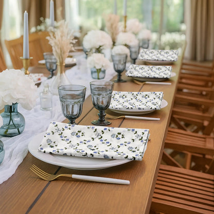 Dining table set with floral-patterned plates, glasses, and cutlery in a bright room.