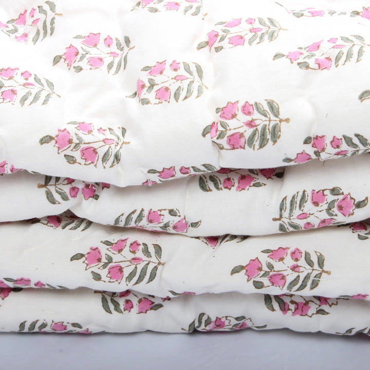 Stack of white fabric with pink floral patterns on a light gray background