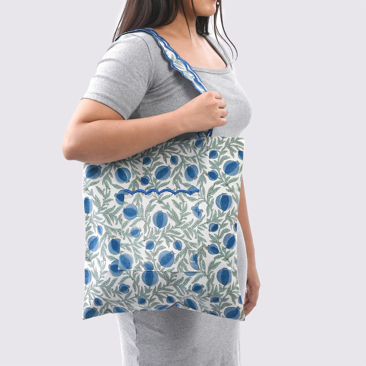 Woman wearing a gray t-shirt with a floral apron over it on a white background