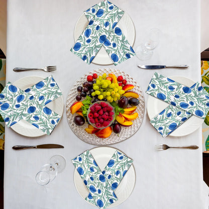 Table setting with floral-patterned plates and napkins, featuring a fruit platter in the center.