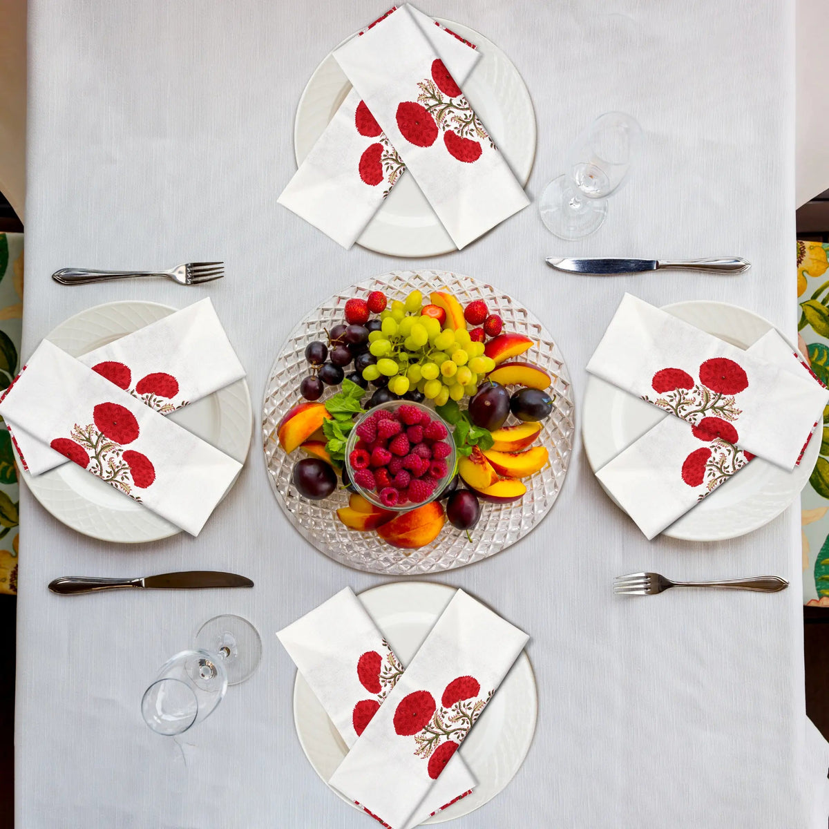 Elegant table setting with fruit platter and decorative napkins on a white tablecloth.