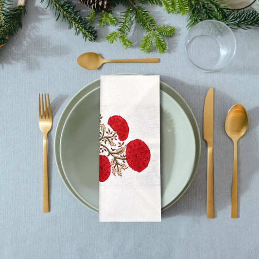 Table setting with a decorative napkin featuring red floral patterns on a gray tablecloth.