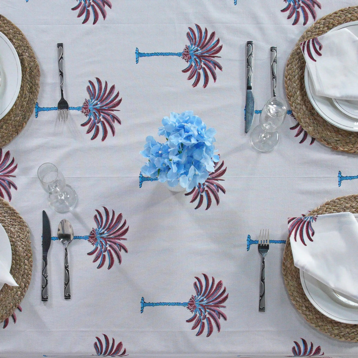 Decorative tablecloth with red and white palm tree pattern on a plain background with striped border