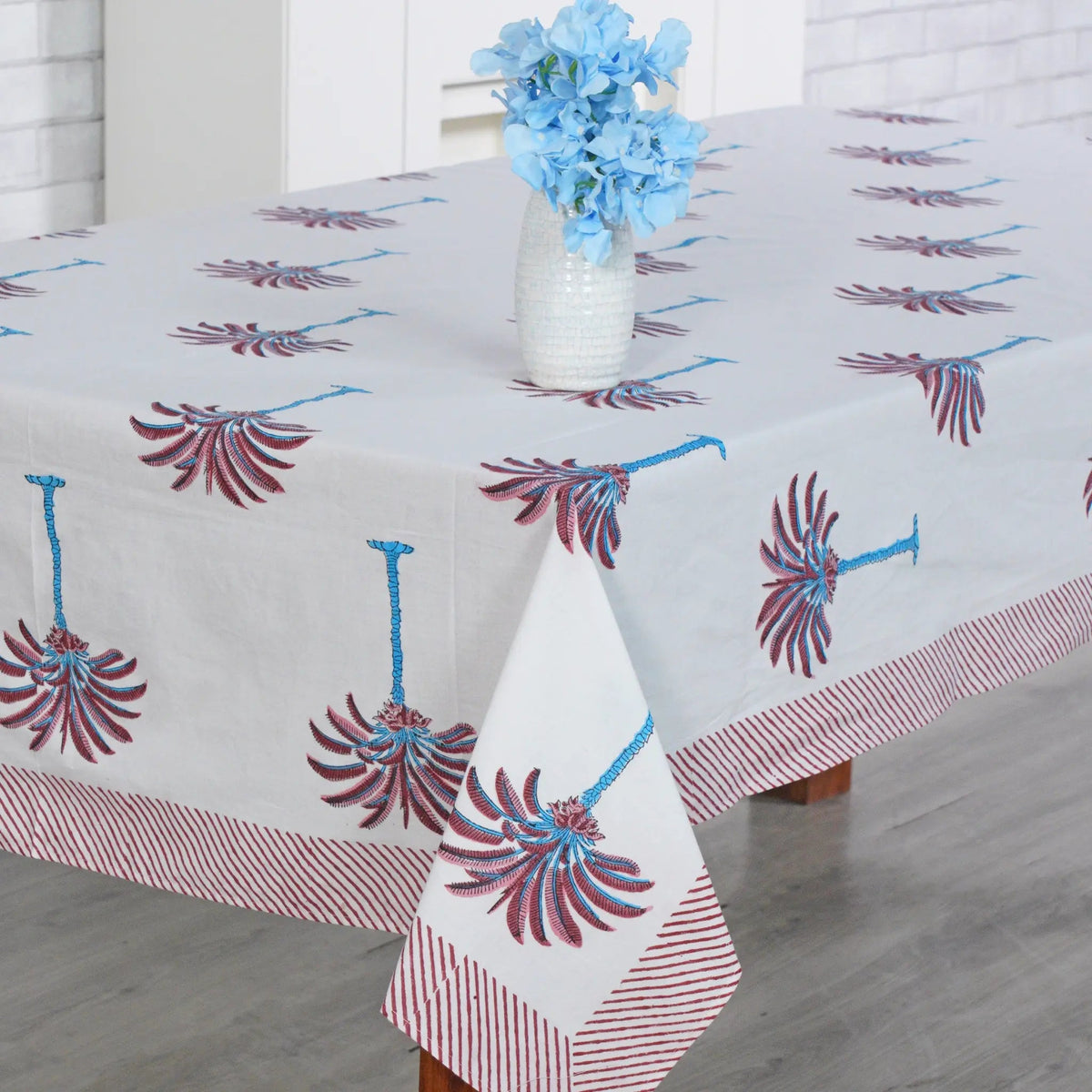 Decorative tablecloth with red and white palm tree pattern on a plain background with striped border