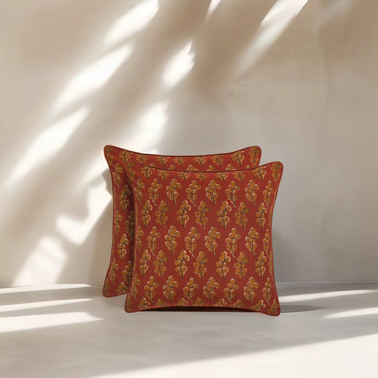Two red patterned pillows on a white surface with soft shadows.