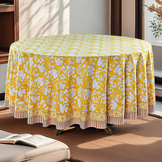 Round table with a yellow and white patterned tablecloth in a room setting.
