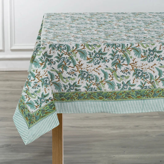 Green floral patterned tablecloth on a wooden table with a white wall background