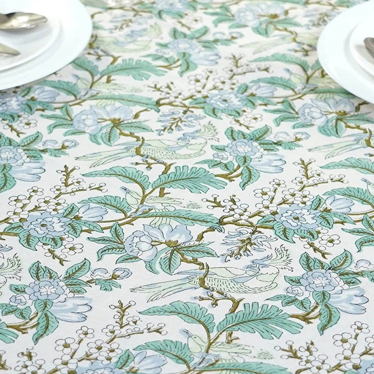 Floral and leaf patterned tablecloth on a table.