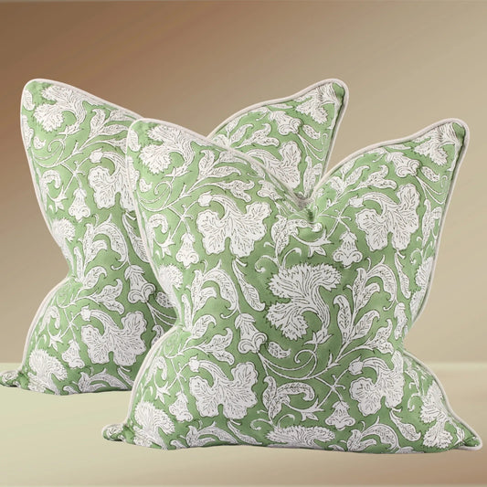two sage green and white floral pillow on brown background