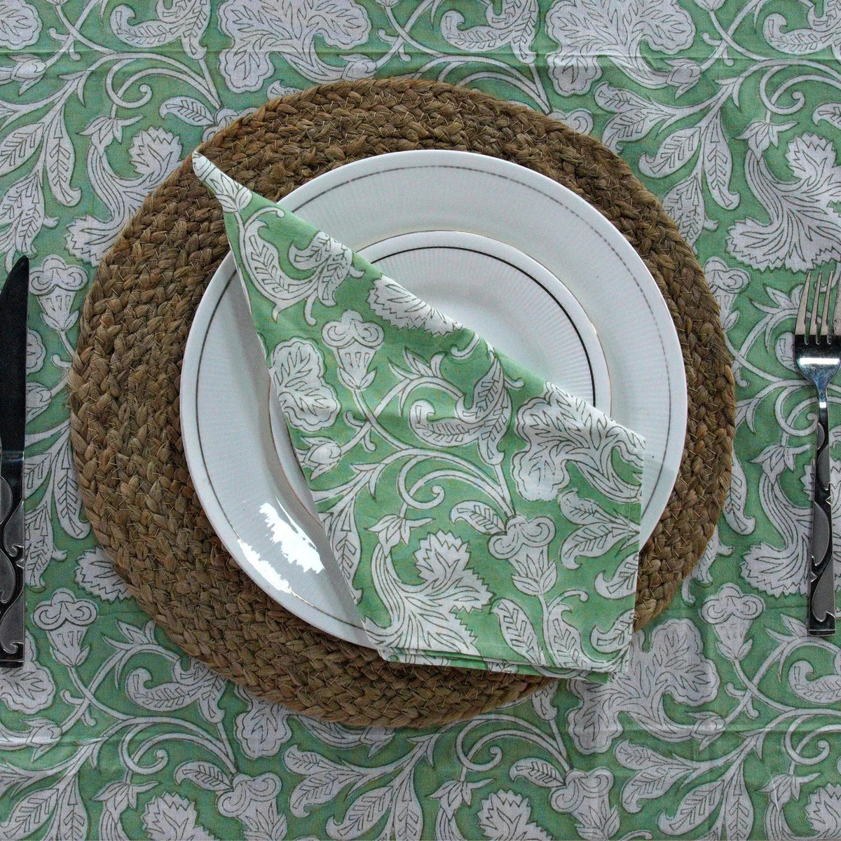 Plated dish with a green and white patterned napkin on a decorative tablecloth.