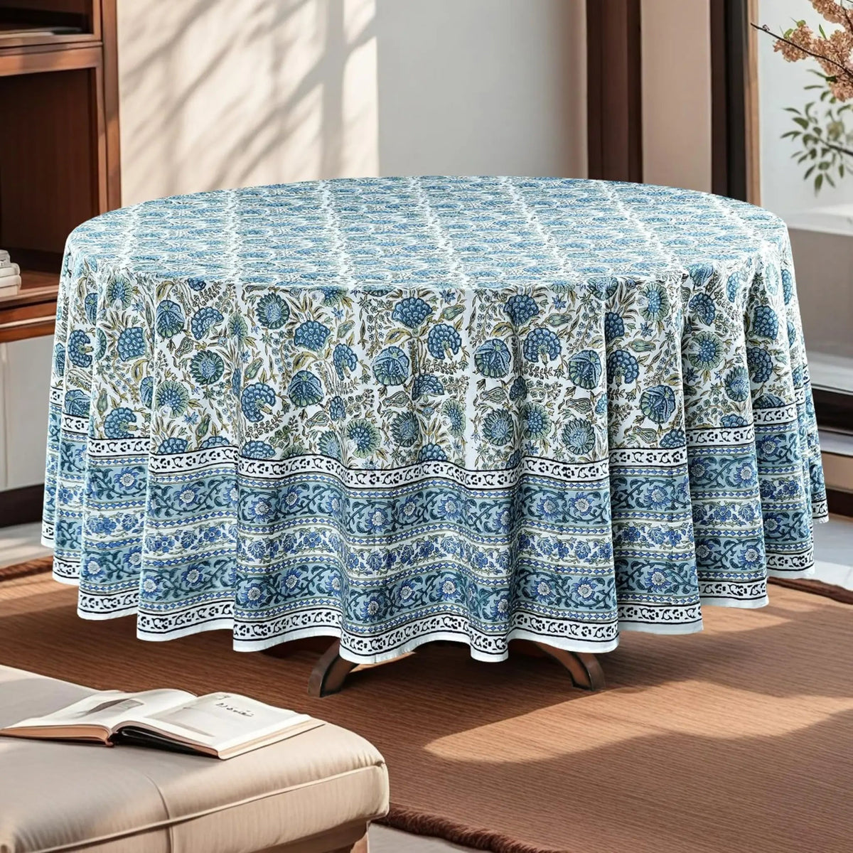 Round table covered with a blue floral patterned tablecloth in a room setting.